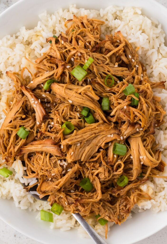 Serving of sweet garlic chicken over rice on a serving plate.