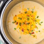 An instant pot with the chowder inside of it and toppings.