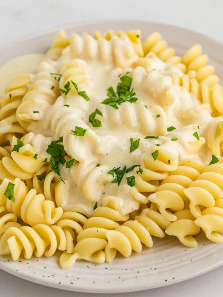 Alfredo sauce with pasta on a white plate with a fork.