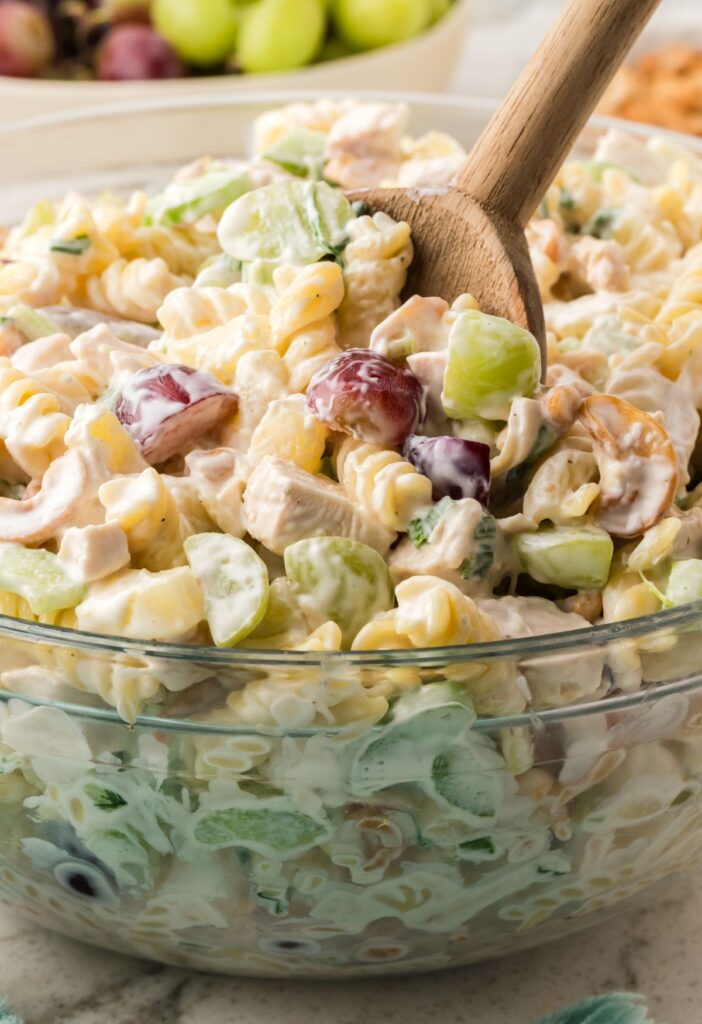 Side view of the bowl with pasta salad and a wooden spoon in it