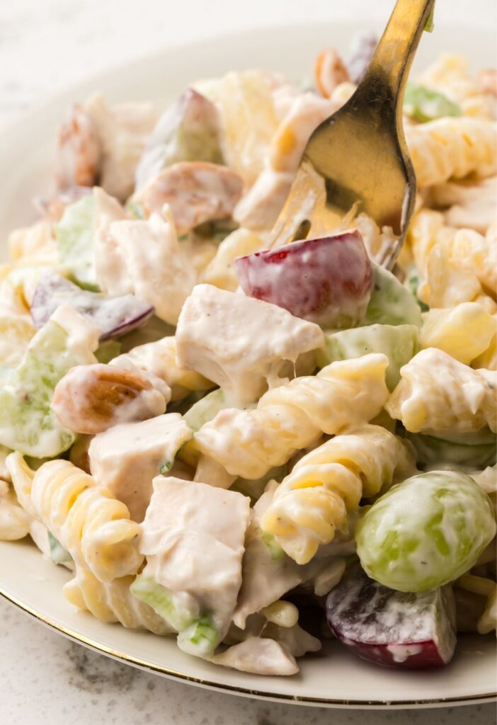 A serving of fruity cashew chicken pasta salad with a fork in it