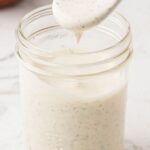 A jar of ranch dressing with a small wooden spoon