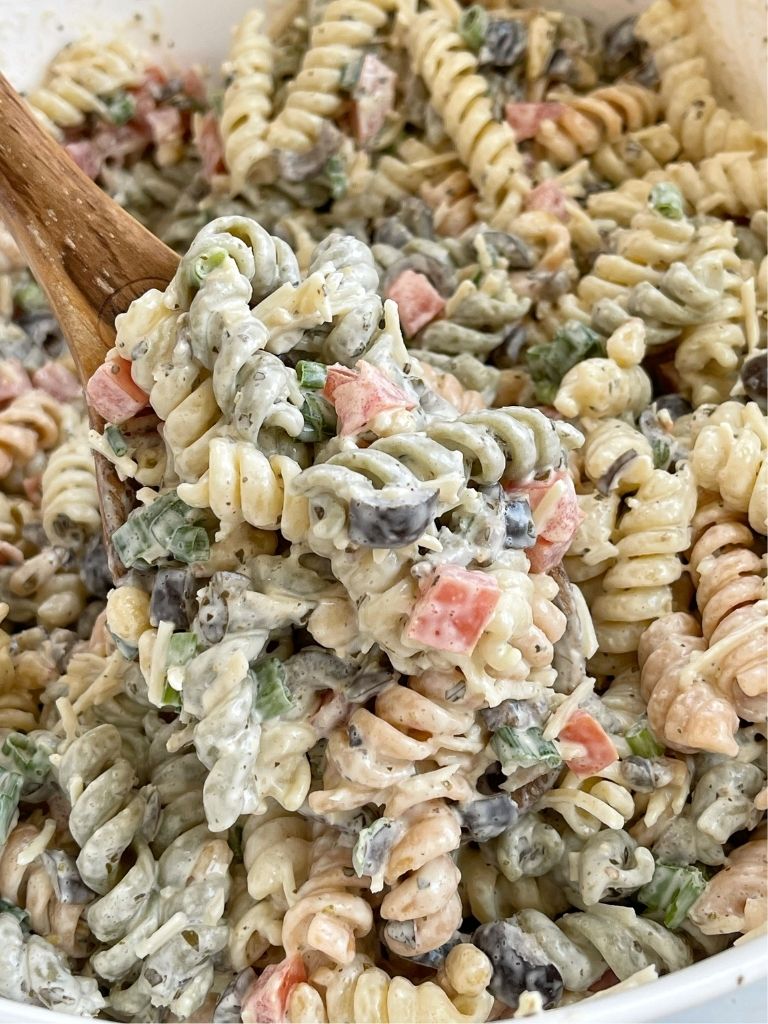 A wooden spoon with pasta salad on it. 