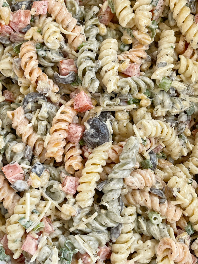 Close up picture of pesto pasta salad inside a white bowl. 