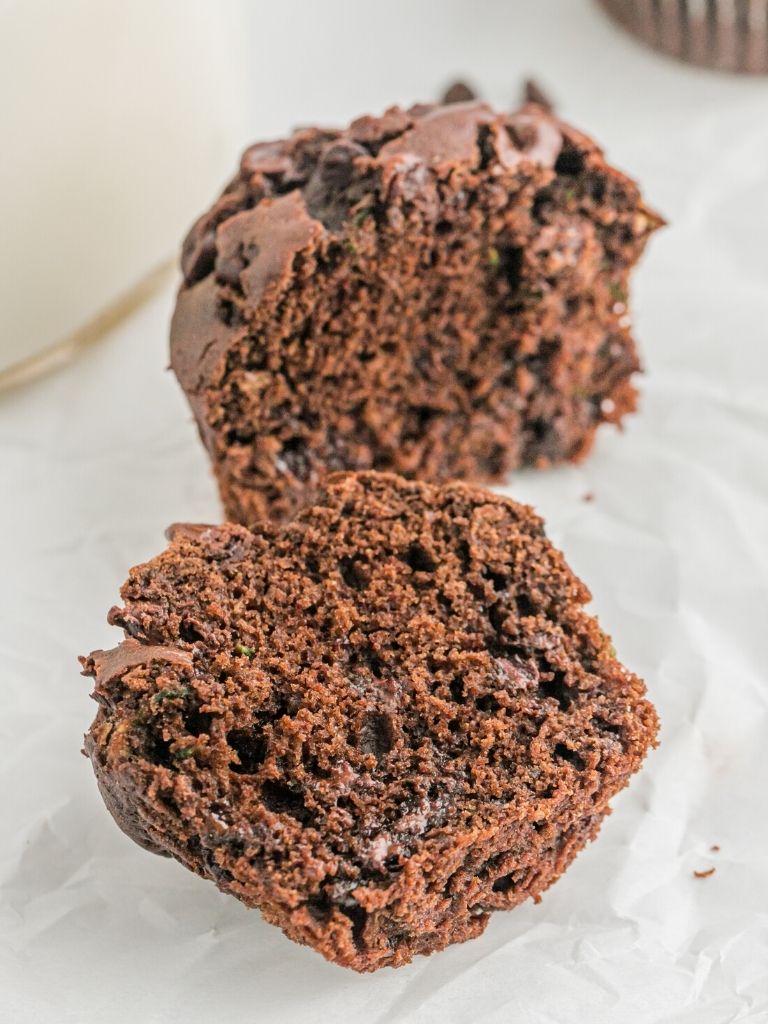 A chocolate zucchini muffin cut in half with the inside showing. 