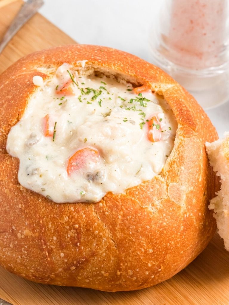 A bread bowl with creamy rice soup inside of it. 