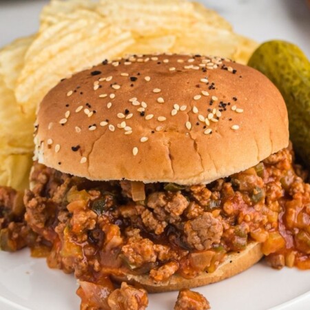Sloppy Joe on a white plate with a crock pot in the background.
