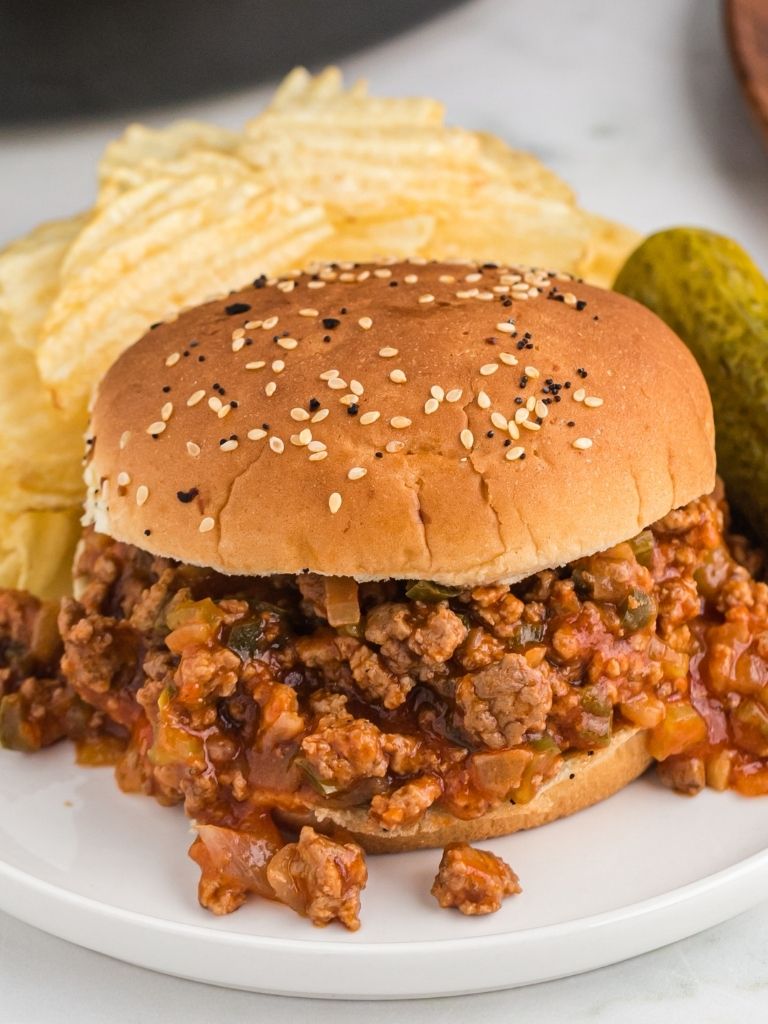 Sloppy Joe on a white plate with a crock pot in the background.