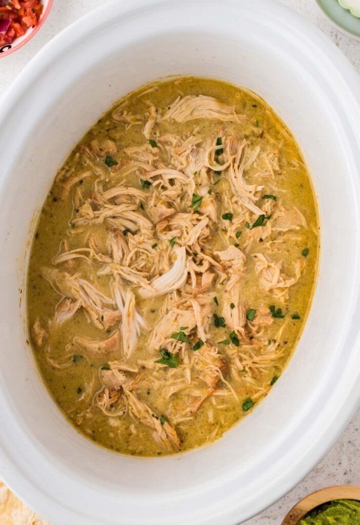 Inside the crockpot with the cooked shredded chicken for tacos in it.