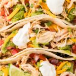 Closes up of the top of the tacos with shredded chicken and all the toppings.