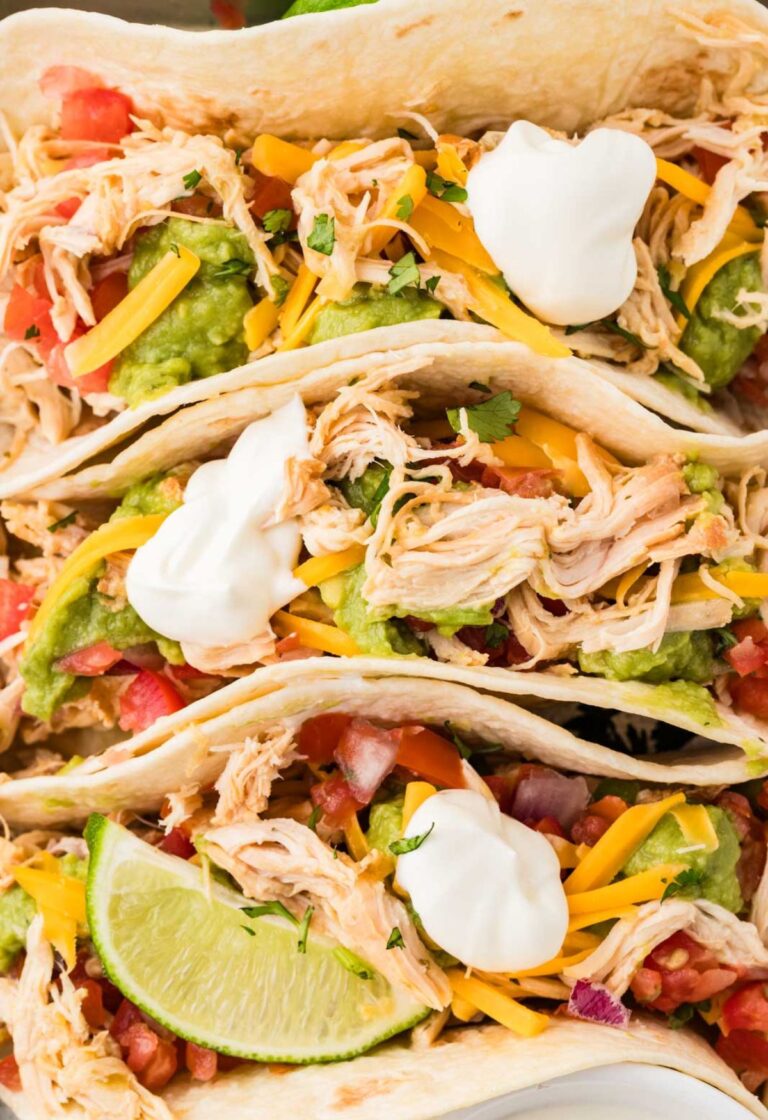 Closes up of the top of the tacos with shredded chicken and all the toppings.
