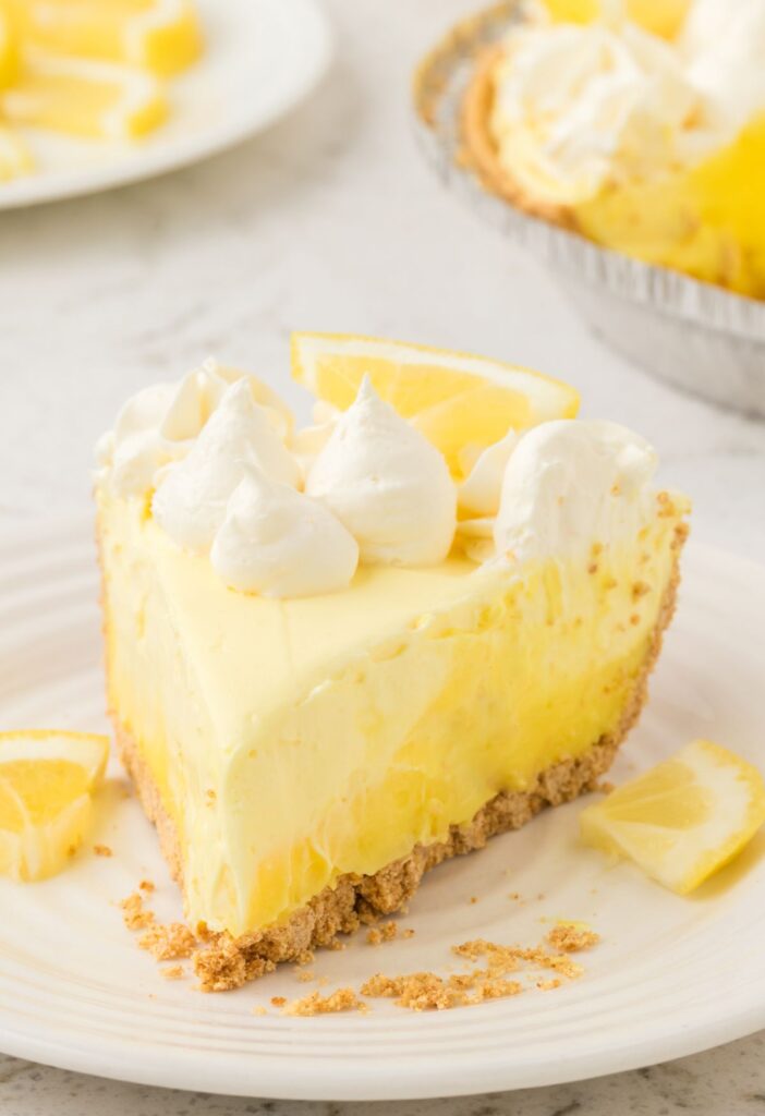 Slice of cheesecake pie with lemon and whipped cream on top.