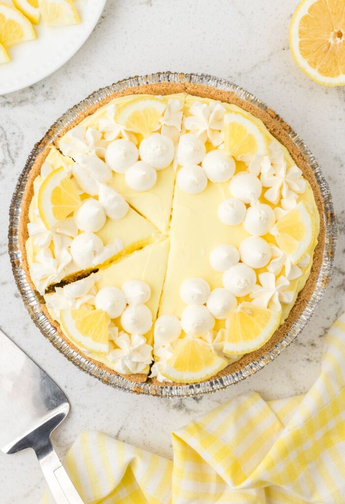 A no bake pie cut into slices with a fresh lemon nearby.