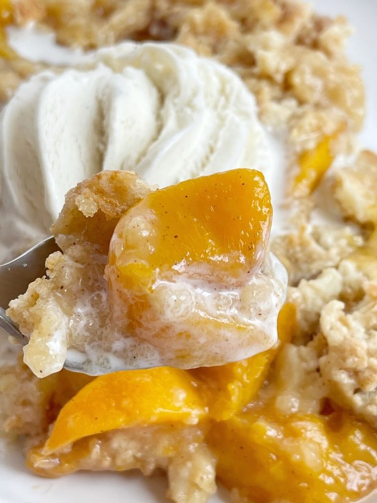 A close up bite of peaches dump cake on a fork.