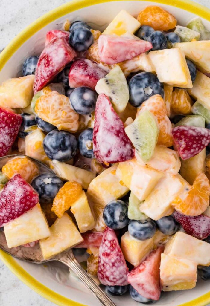 Closes up of the fruit salad in bowl with a serving spoon