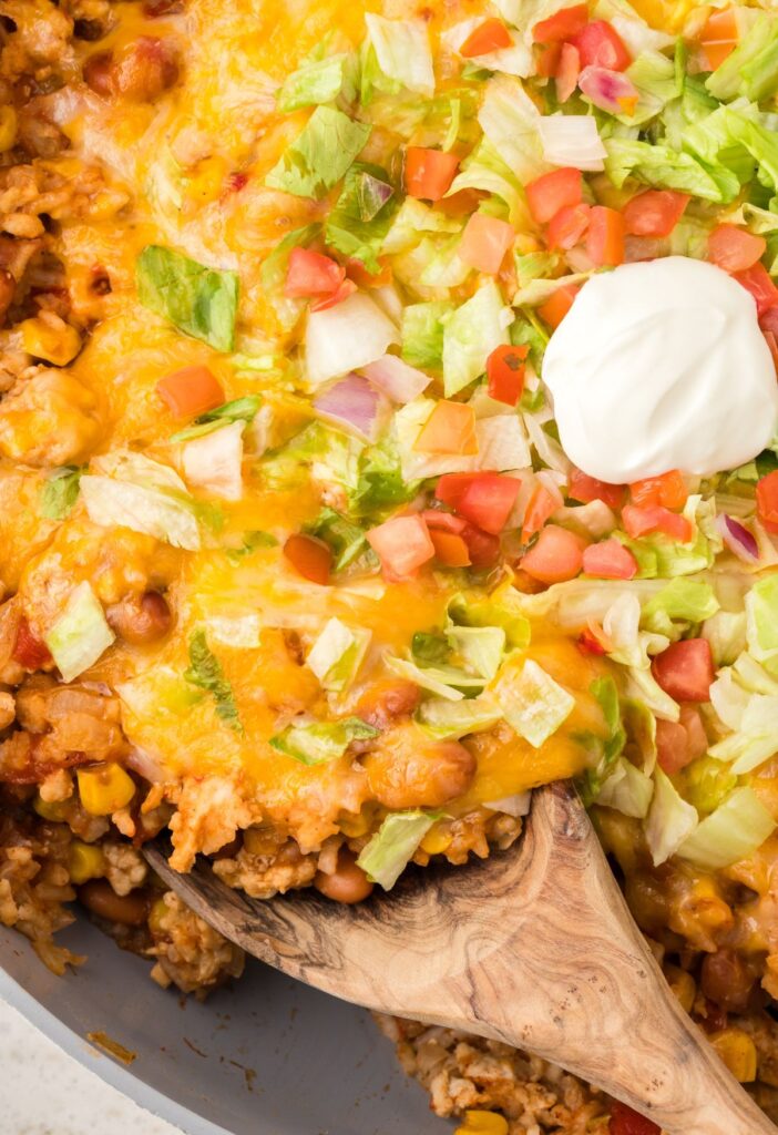 A serving spoon inside the skillet pan dinner