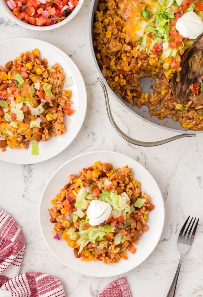 Top view of the skillet pan with serving plates of the taco rice. 