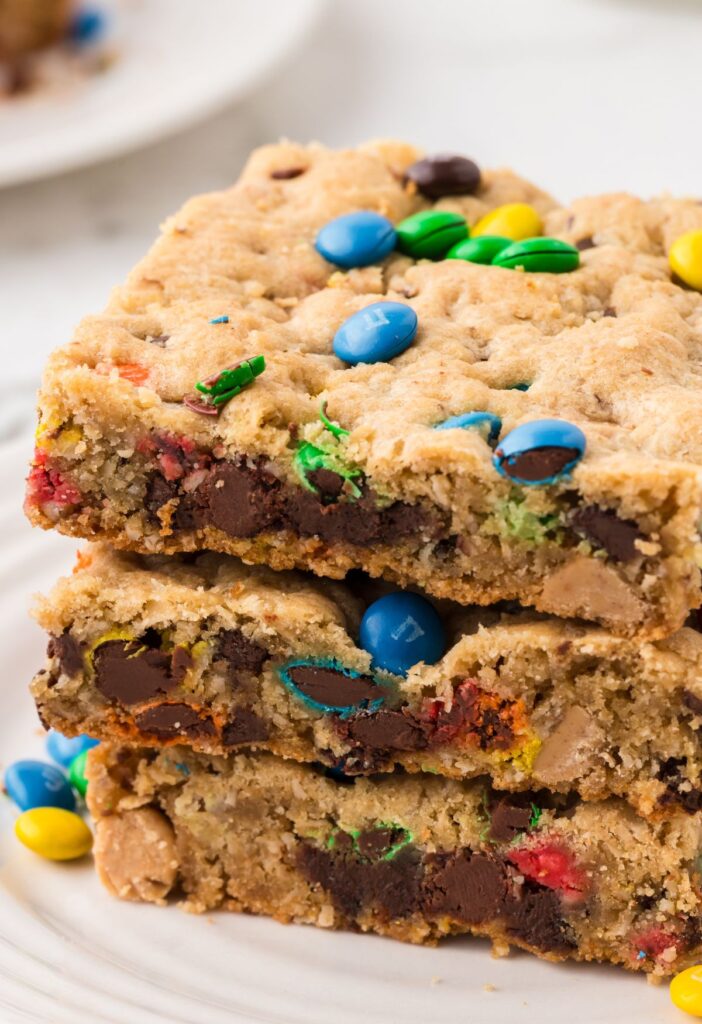 Stack of monster cookie bars on a white plate.