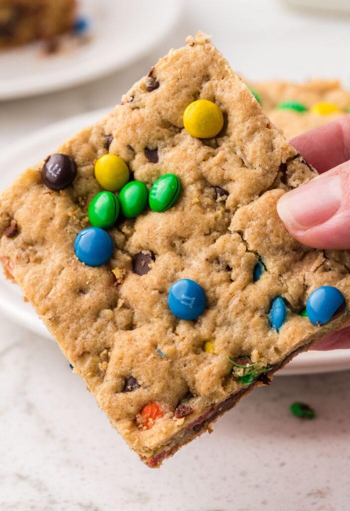 A hand holding a monster cookie bar