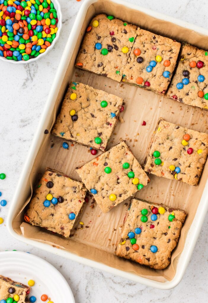 Pan of cookie bars with a bowl of mini m&ms beside it. 