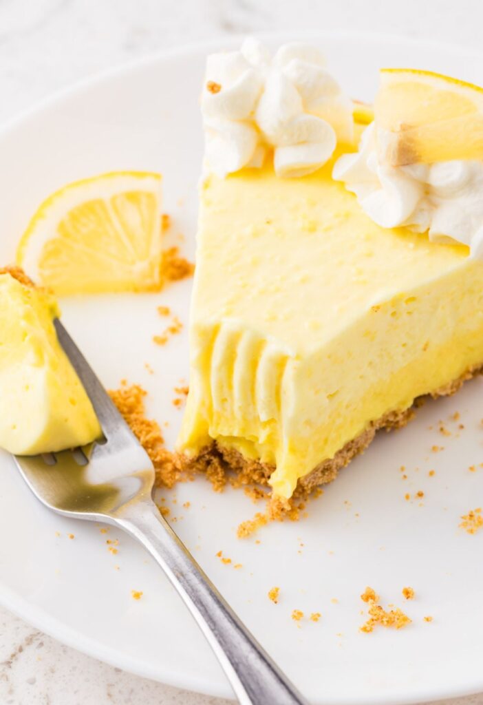 A slice of lemon pie with a fork on the plate