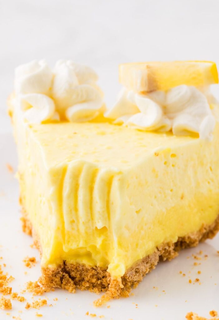 Fornt view of a slice of lemon pie with a fork bite taken out of the front.