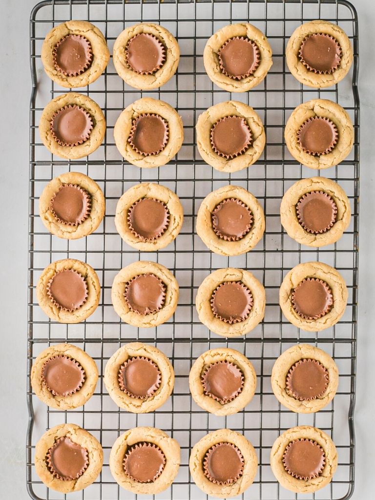 Cooling rack of cookie cups with peanut butter on the in a row.