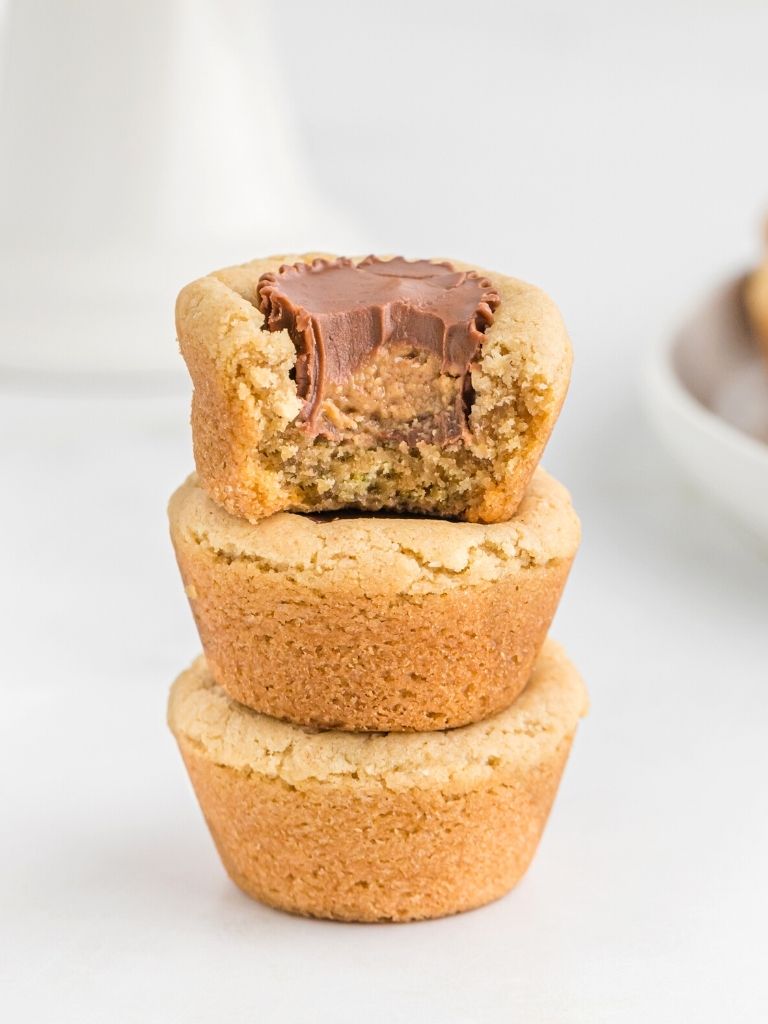 Stack of 3 peanut butter cookies on top of each other. Cookie cups with a Reese's inside of them. 