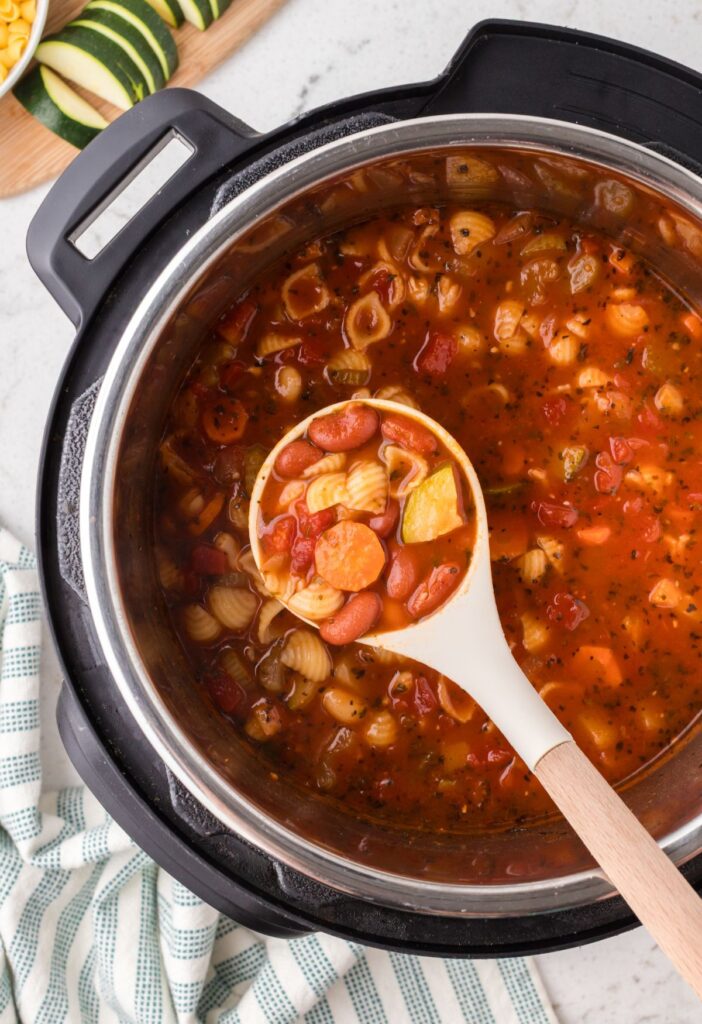 A soup ladle with minestrone soup in it