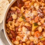 Top view of a bowl of minestrone soup with bread slices.