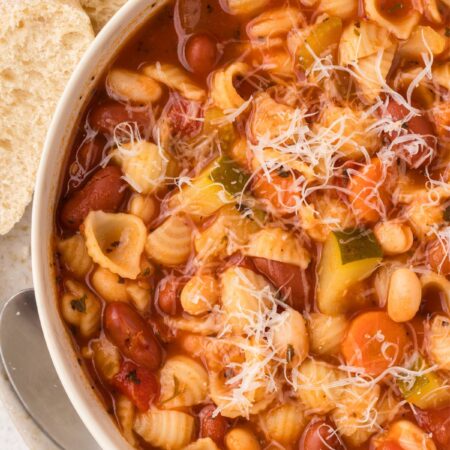 Top view of a bowl of minestrone soup with bread slices.