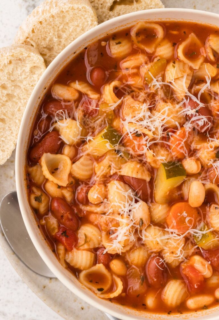 Top view of a bowl of minestrone soup with bread slices.