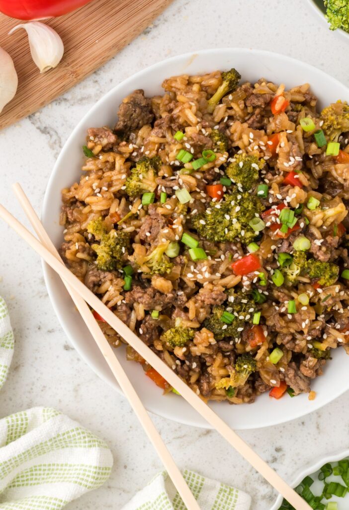 Serving bowl of the teriyaki beef and rice with chopsticks on the bowl.
