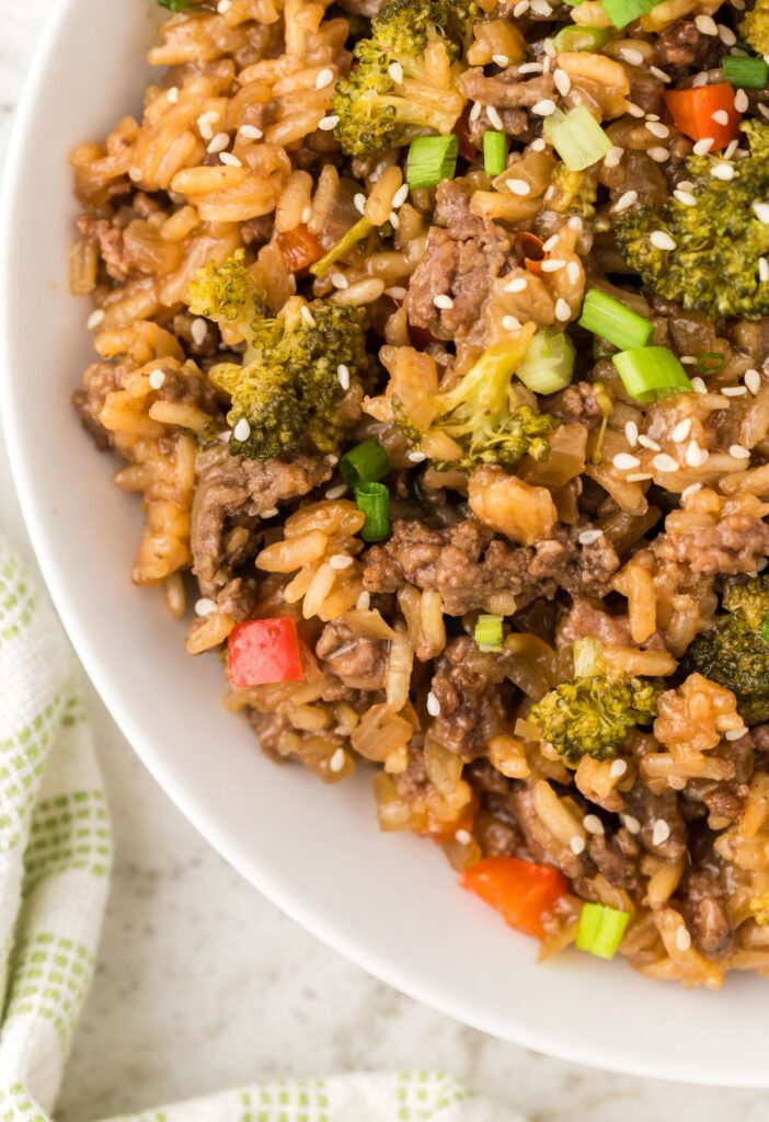 White bowl with ground beef and rice with teriyaki sauce and vegetables. 