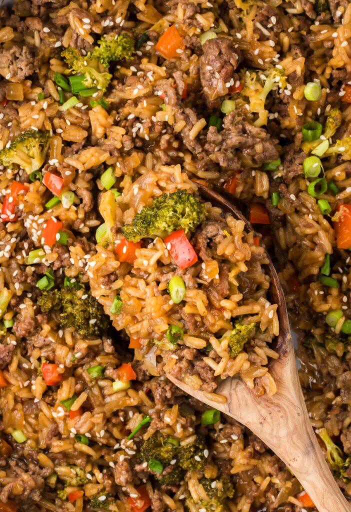 Overhead pic of the skillet pan of teriyaki beef and rice with a wooden serving spoon in it. 