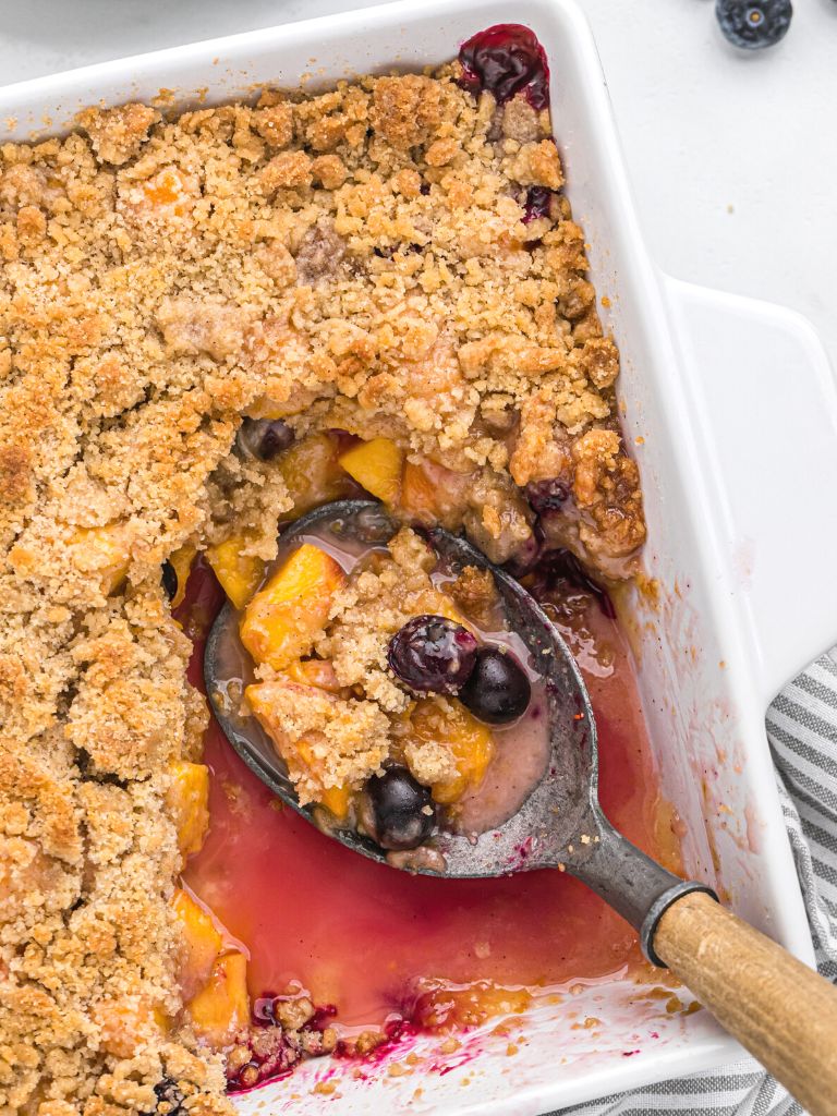 A white baking dish with cooked fruit crisp inside of it. 