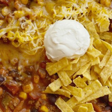 Taco Chili cooks in one pot on the stove! Ground beef, veggies, beans, and tomatoes simmer in a seasoned beef broth tomato base. The secret ingredient of cocoa powder makes this chili the best! Top with tortilla chips, sour cream, and cheese.