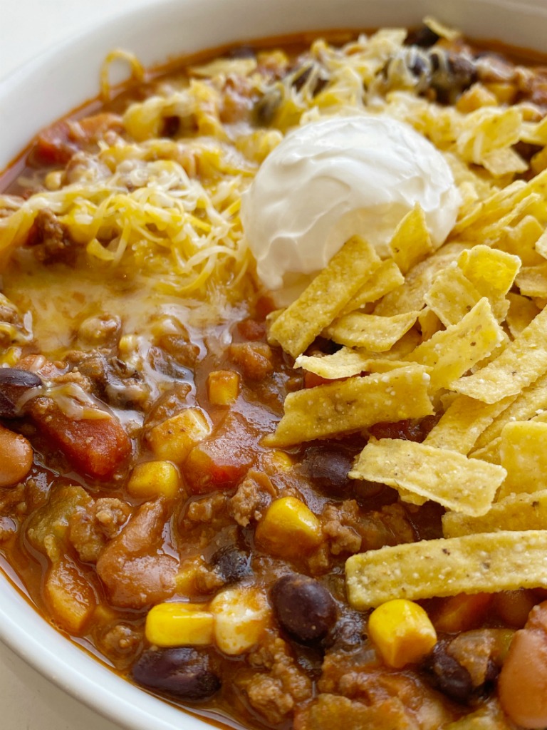 Taco Chili cooks in one pot on the stove! Ground beef, veggies, beans, and tomatoes simmer in a seasoned beef broth tomato base. The secret ingredient of cocoa powder makes this chili the best! Top with tortilla chips, sour cream, and cheese. 