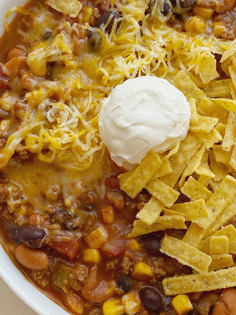 Taco Chili cooks in one pot on the stove! Ground beef, veggies, beans, and tomatoes simmer in a seasoned beef broth tomato base. The secret ingredient of cocoa powder makes this chili the best! Top with tortilla chips, sour cream, and cheese. 