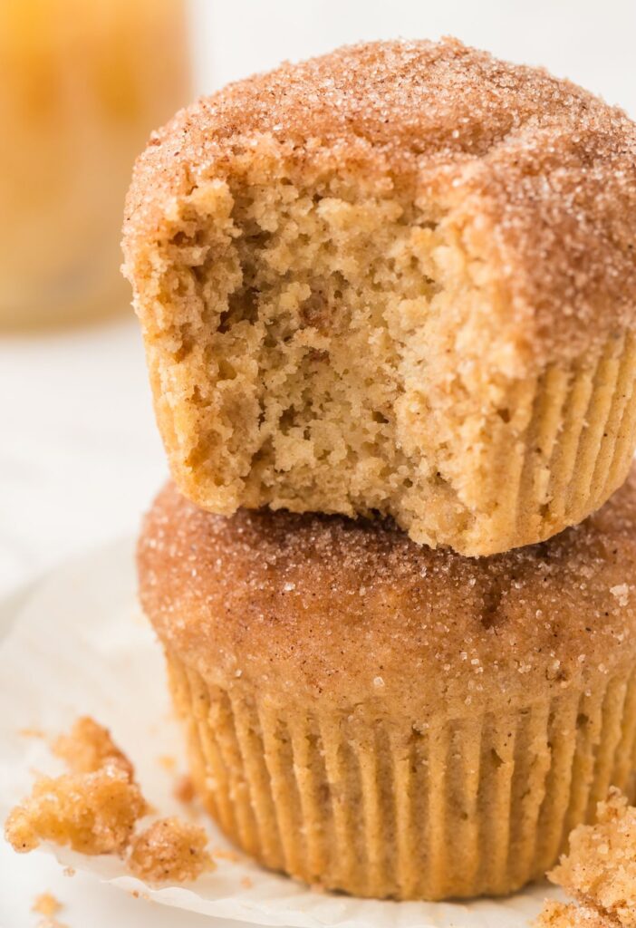 Stack of two muffins with the top having a bite taken out of it.
