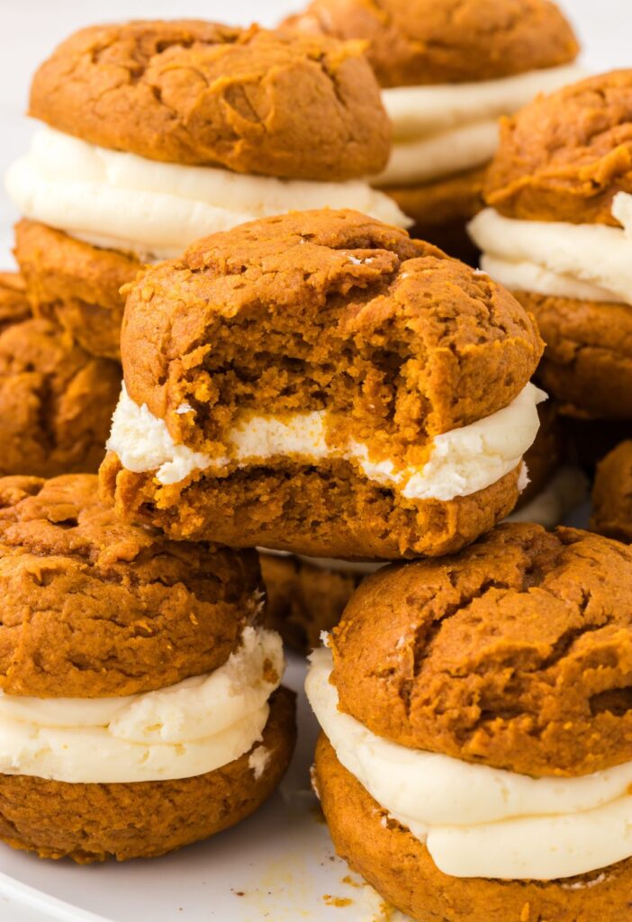 Pumpkin whoopie pies stacked on a plate.