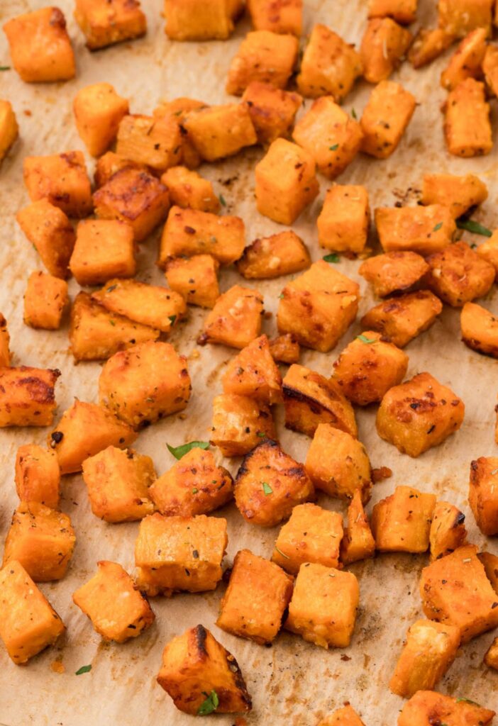 A baking sheet lined with parchment paper with the roasted sweet potatoes on it. 