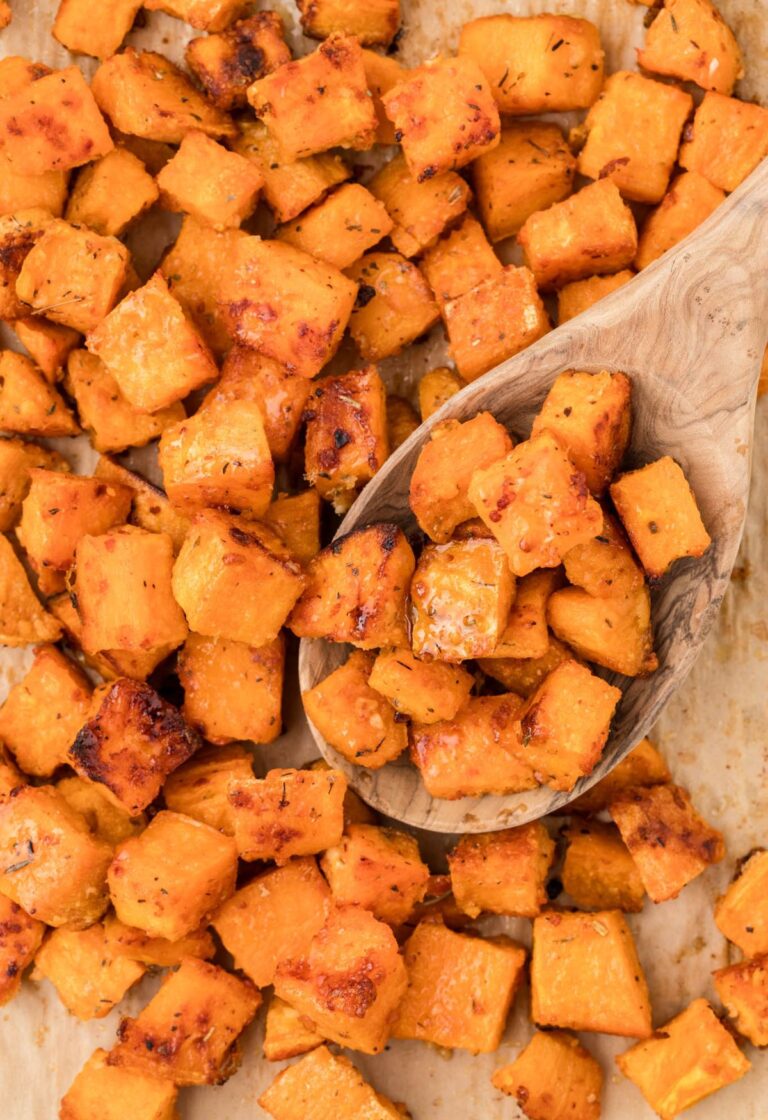 A pan of baked sweet potatoes with a wooden spoon holding some.
