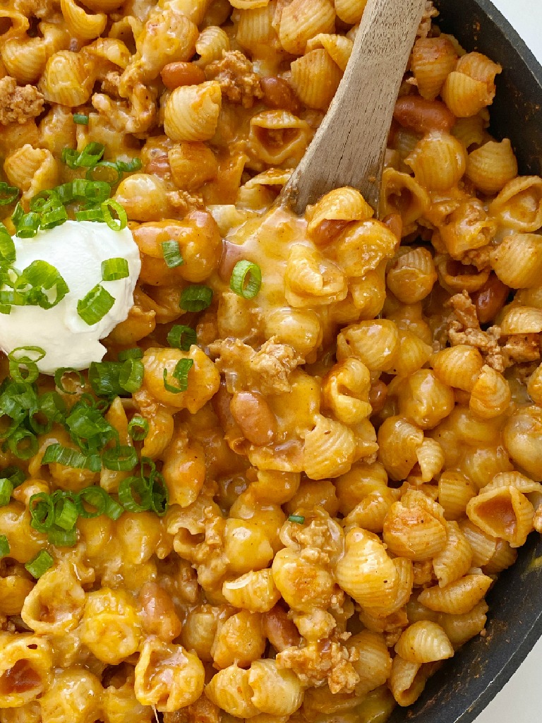 Turkey Chili Mac and Cheese is made in just one pot! Ground turkey chili with pinto beans cooks in a seasoned tomato sauce and chicken broth base with small shell pasta. Add lots of cheese for a cheesy and creamy mac and cheese with turkey chili!