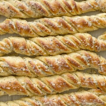Easy Breadsticks Recipe are a family favorite because of their fun twisty shape. Quick & easy to make and the perfect recipe for beginners. Soft breadsticks filled with garlic butter and topped with parmesan seasoned butter.