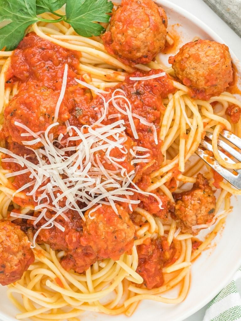 Plate of spaghetti noodles with meatballs and sauce. Fork on the plate.