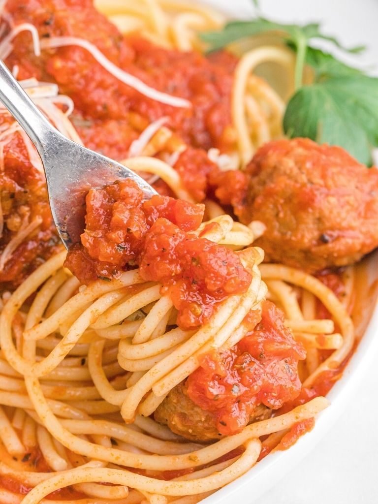 A fork twirling some spaghetti in it with meatballs. 
