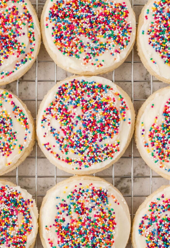 Overhead to view of the sugar cookies on a cooling rack with frosting and sprinkles on them. 