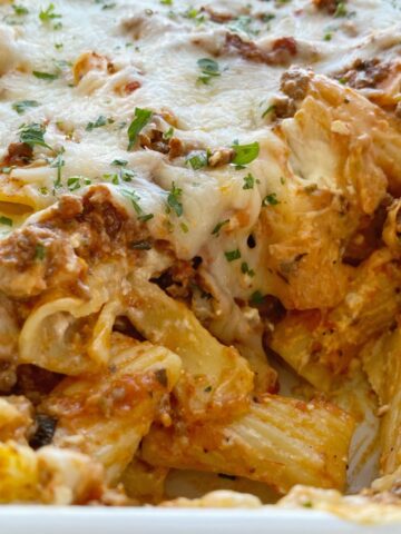 Close up shot of cheesy and creamy lasagna casserole with rigatoni pasta noodles.