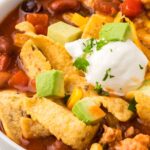 A white bowl of turkey taco soup with toppings for serving.